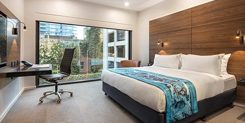 Poolside guestroom with 2 double bed, work desk & sofa chair near wall to ceiling window